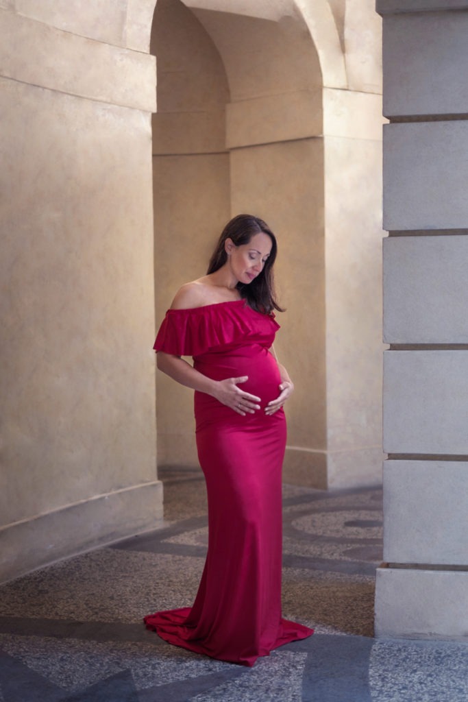 Mother to be with red dress in a grotta at Havlickovy sady, Prague, Czech republic